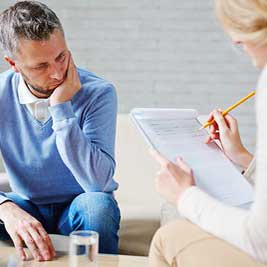 Two adults at a table, one is writing on a pad.