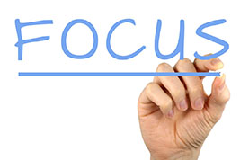 Hand writing the word 'focus'.